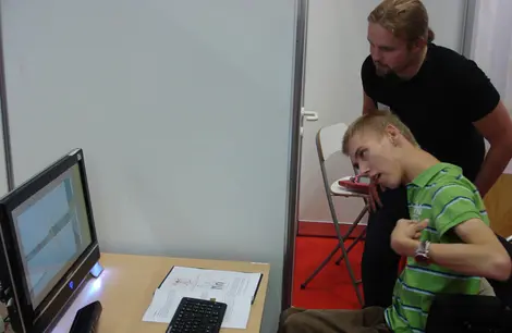 Junger Mann im Rollstuhl steuert den PC mit Microsoft Kinect.