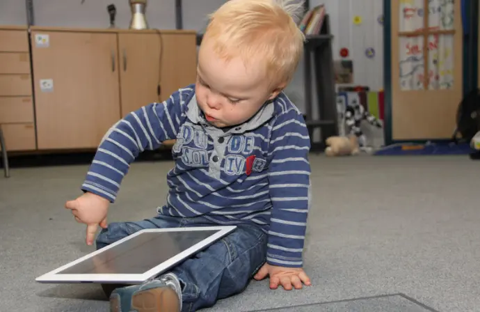 Kleiner Bub mit Down Syndrom bedient ein iPad.