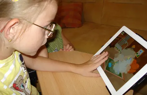 Ein Mädchen mit Rett Syndrom spielt am iPad.